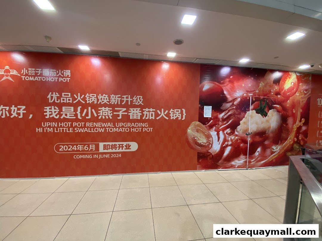 A shop front with a large orange banner announcing the renewal and upgrade of Tomato Hot Pot.