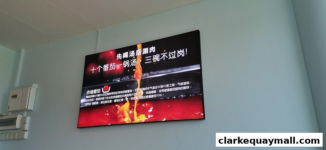 A digital screen displays an advertisement for tomato hot pot with vibrant imagery and text.
