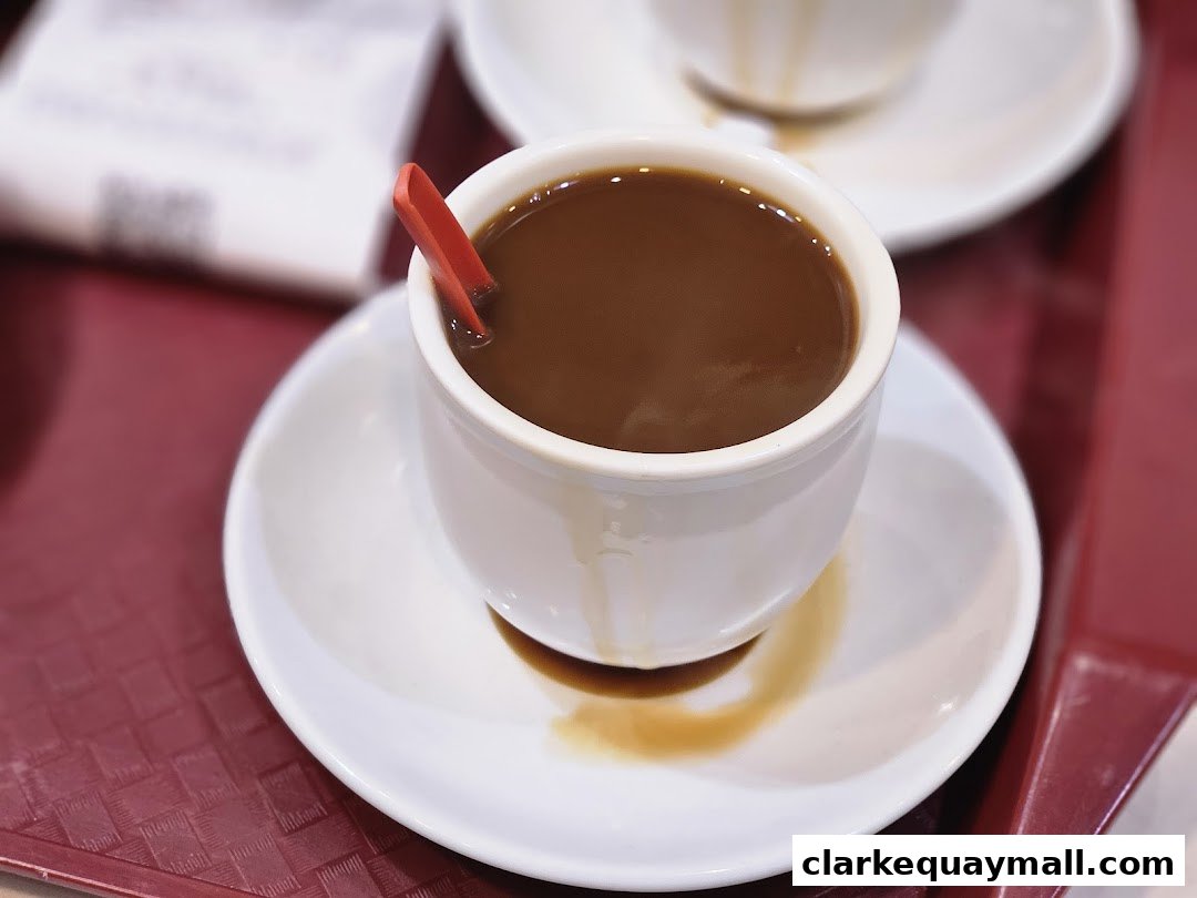 A close-up of a steaming cup of coffee with a red stirrer on a saucer.