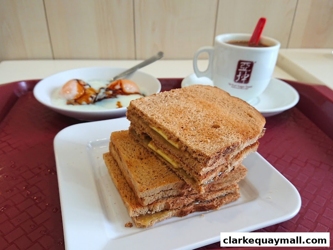 A close-up of Ya Kun Kaya Toast's signature kaya toast, soft-boiled eggs, and coffee.
