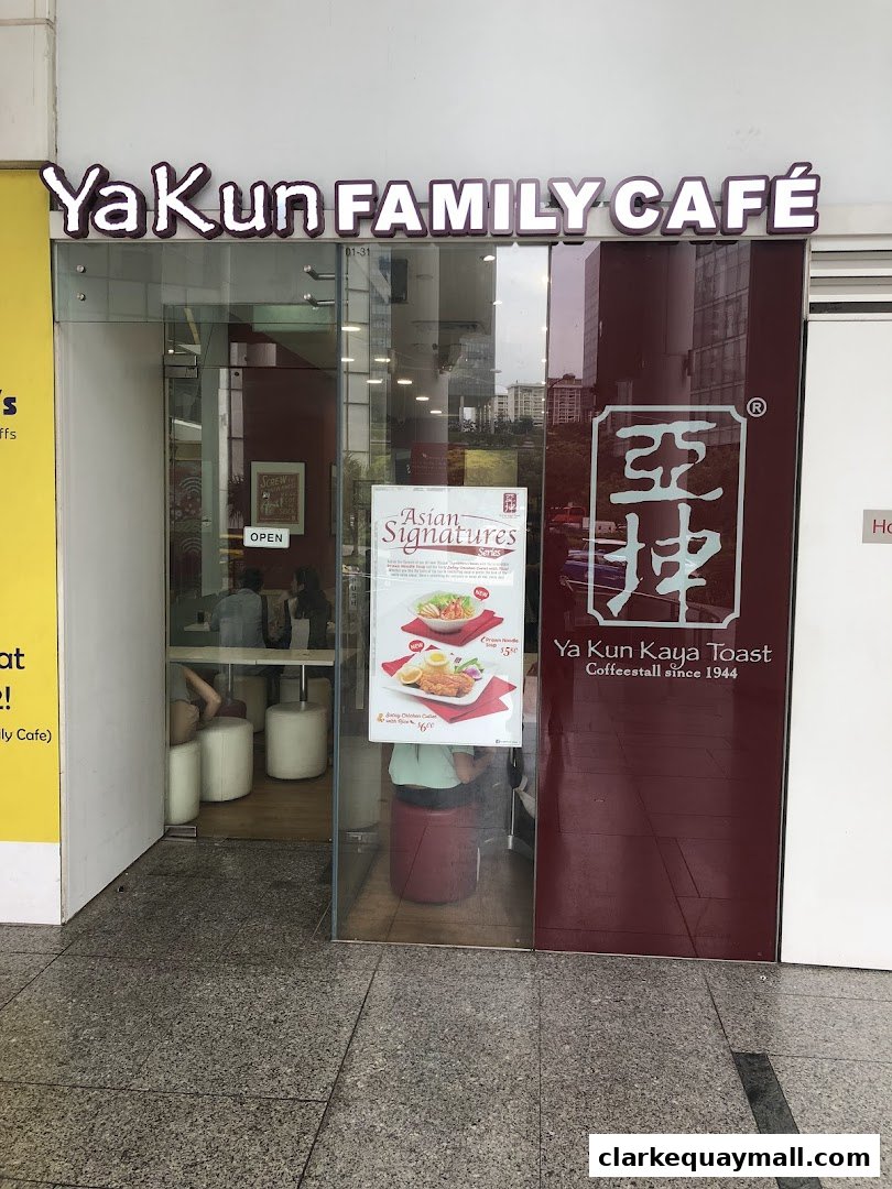 The entrance of Ya Kun Family Cafe, featuring its prominent signage and a promotional poster.