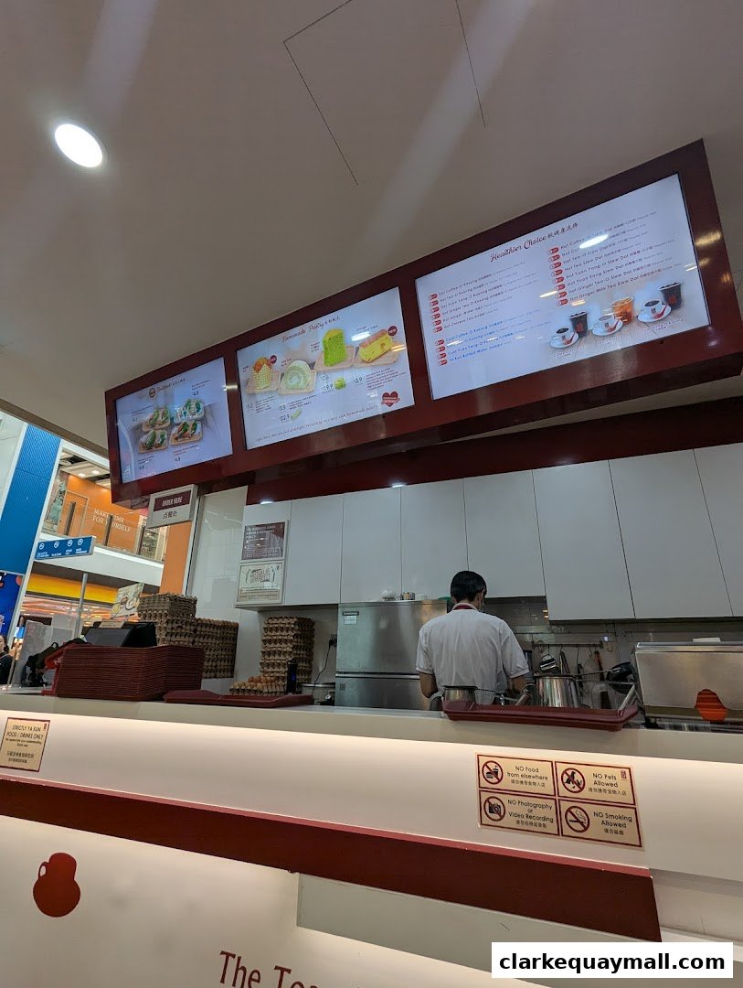 A counter at Ya Kun Kaya Toast with menus displayed above and a staff member preparing food.