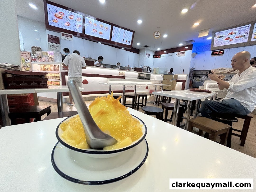 A dessert is served in a bowl with a spoon, inside a clean and modern cafe.