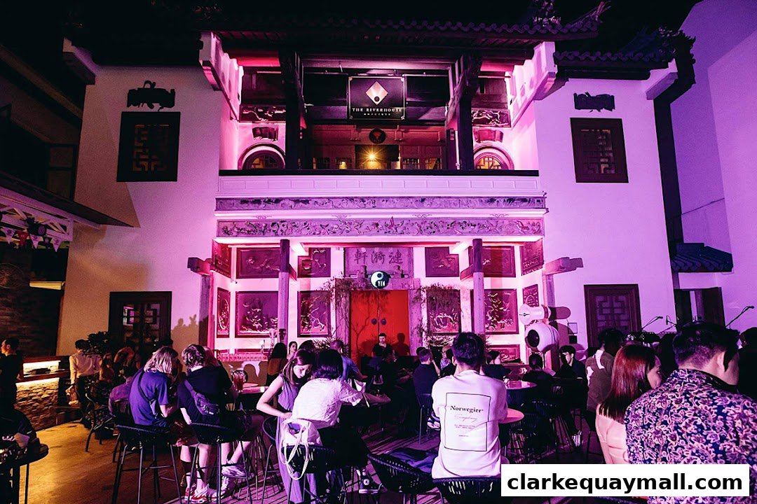 A lively bar interior with people seated at tables and a bar, illuminated by purple lighting.