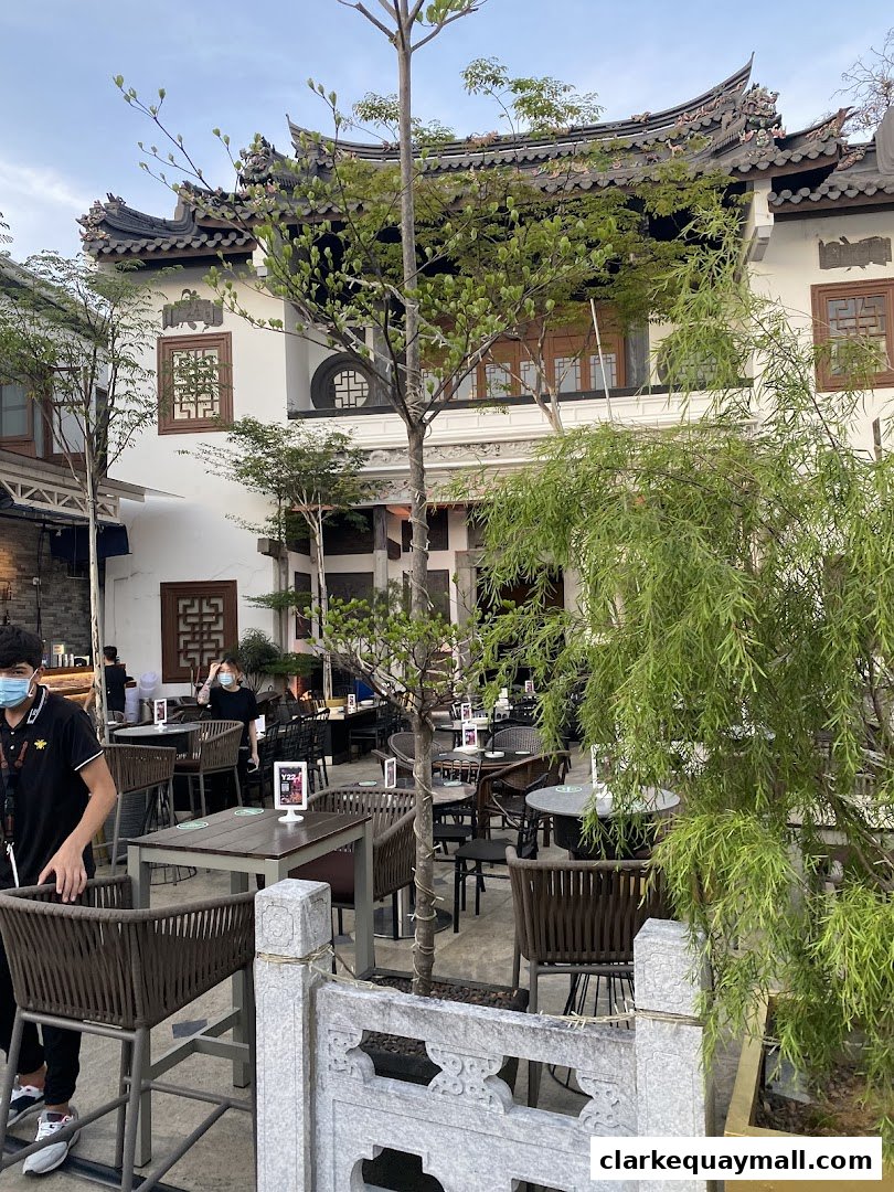An outdoor seating area of a restaurant with traditional architecture and lush greenery.