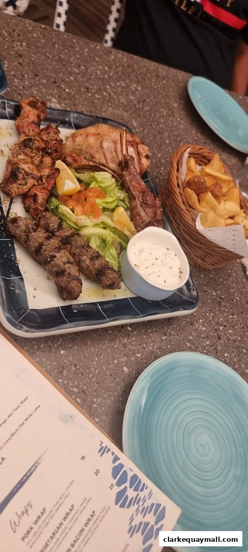 A platter of grilled meats, salad, and dips, with a basket of fries.