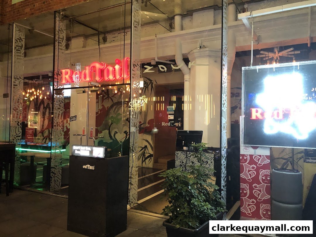The illuminated "Red Tail" sign above the entrance of a modern restaurant at night.