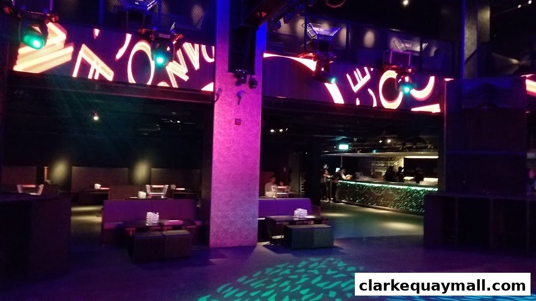 Interior view of a nightclub with lounge seating, a bar, and illuminated signage.