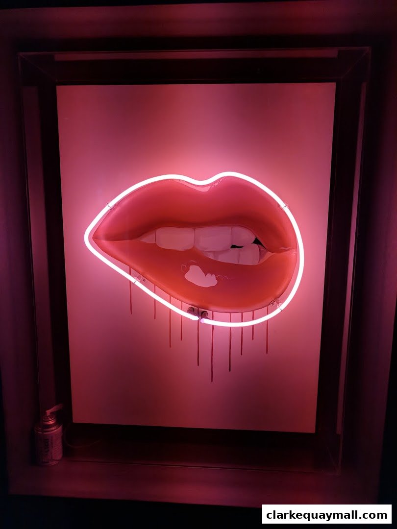 A neon sign of red lips with dripping effect against a pink background.