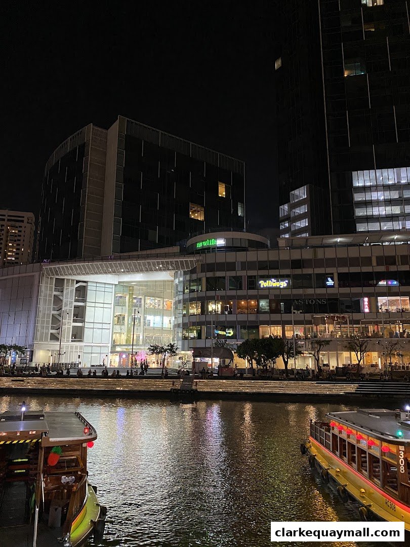 Night view of a waterfront with illuminated buildings and boats.