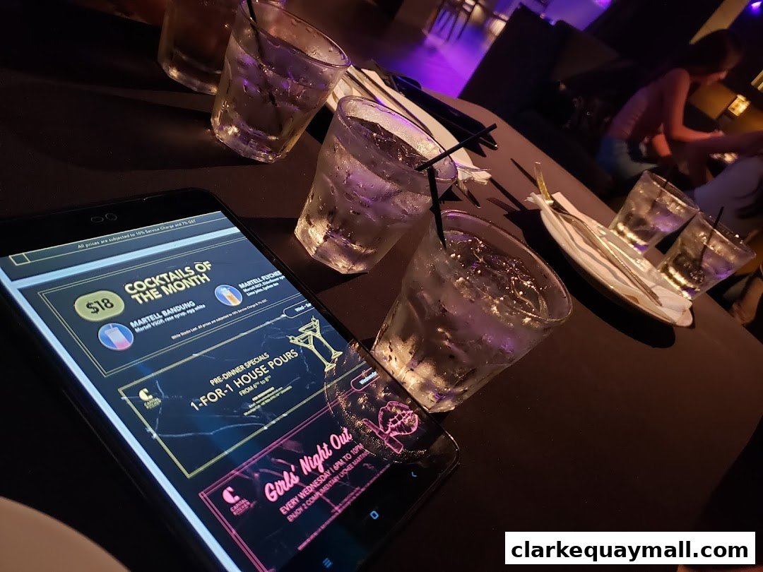 A phone displays a menu with cocktails, house pours, and a girls' night out special.