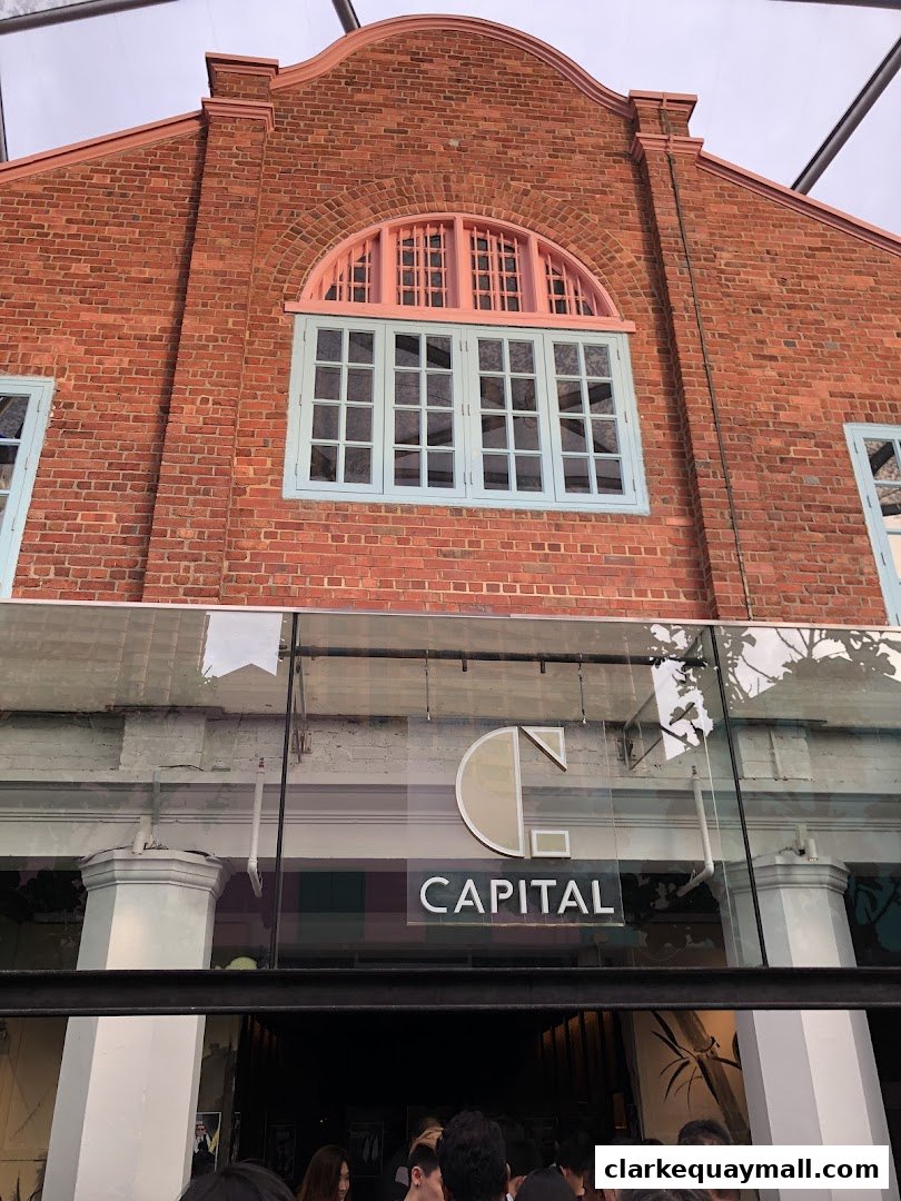 The exterior of a brick building with a large arched window and the "CAPITAL" logo above the entrance.